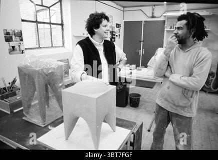 Two artists 'The Mill' Heemstede Heemstede The Netherlands, Whizgle News, Dutch Desk, The Netherlands, 1950 - 2000 on 24-10-1995. The image shows these topics. Within a creative studio space, two individuals engage in conversation, surrounded by various artistic tools and materials. The setting features large windows through which soft, natural light streams, creating a warm and inviting atmosphere. The two people stand near a wooden table that supports a partially crafted sculpture, showcasing a unique design with elegant curves and a minimalist aesthetic. The first individual, dressed in a c Stock Photo