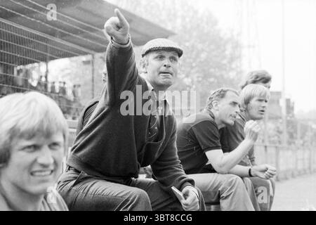 Football match Haarlem - FC Den Haag (trainer Barry Hughes), Whizgle News, Dutch Desk, The Netherlands, 1950 - 2000 on 04-06-1979. These topics are shown in the image. The scene features a group of five individuals seated along the edge of a sports field or stadium. The atmosphere conveys a sense of anticipation and engagement, possibly during a match or training session. In the foreground, a man with light-colored hair and a serious expression is watching intently, suggesting he might be analyzing the game or offering support to a team. His casual attire, consisting of a dark sweater, indicat Stock Photo