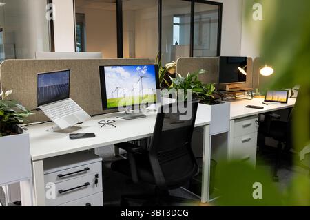 Workspace featuring monitors showing wind turbines, with devices, decor, seating by fabric divider Stock Photo