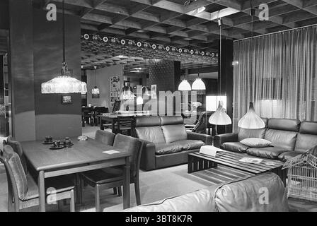 Interior Interior Julianapark Interior Shops and kiosks Haarlem Julianapark The Netherlands, Whizgle News, Dutch Desk, The Netherlands, 1950 - 2000 on 04-05-1976. The image shows these topics. In a stylish interior space, the setting is a modern living area with a warm and inviting ambiance. The color palette features soft earth tones, predominantly browns, creams, and subtle shades of gray, creating a soothing atmosphere. To one side, a series of plush leather sofas, characterized by their rich brown hue, are arranged in an inviting manner. The cushions are comfortable and generously sized, o Stock Photo