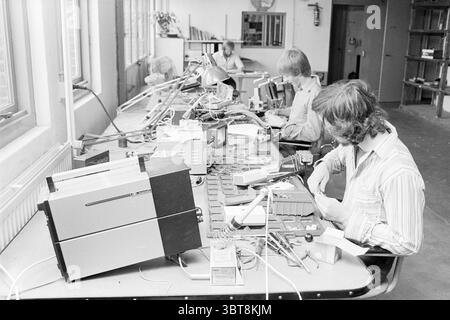Petronics Lisse (equipment for the disabled) Invalids Lisse Heereweg, Whizgle News, Dutch Desk, The Netherlands, 1950 - 2000 on 10-07-1978. These topics are shown in the image. In a spacious, well-lit workshop, several individuals are engaged in meticulous work at a long table. The scene features a harmonious blend of industrial elements and a creative atmosphere. The foreground showcases two workers, both focused intently on their tasks. One person is seated on the left, wearing a striped shirt, with hair that falls slightly over their face, while their hands finely manipulate small component Stock Photo