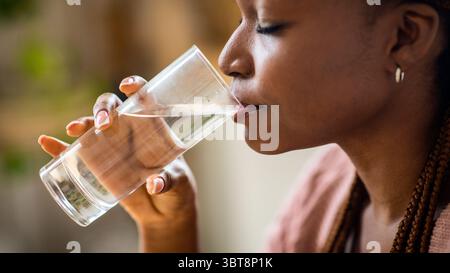 Closeup Shot Of Young Black Woman Drinking Mineral Water From Glass Stock Photo