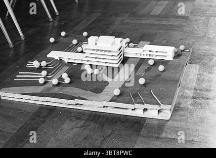 Model Noordwijk Town Hall Model, Whizgle News, Dutch Desk, The Netherlands, 1950 - 2000 on 24-10-1967. The image shows these topics. The scene features a detailed architectural model, showcasing a modern building design that is presented on a flat, textured base. The structure consists of multiple levels, characterized by sleek lines and a minimalist aesthetic. Its rectangular form is comprised of simple geometric shapes, featuring large window-like openings that suggest an emphasis on natural light. Surrounding the building are small, spherical objects that represent trees or landscaping elem Stock Photo