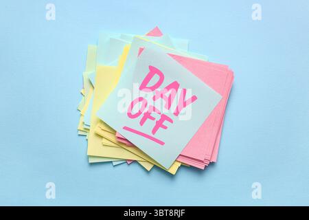 Paper notes with text DAY OFF on blue background Stock Photo