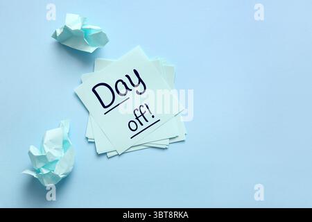 Paper notes with text DAY OFF on blue background Stock Photo
