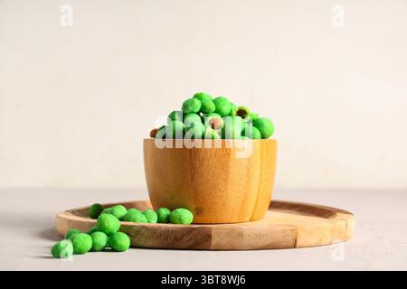 Bowl with wasabi coated crunchy peanuts on light background Stock Photo