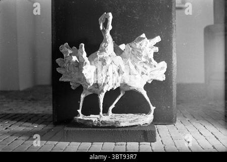 Visual arts. 2 birds, Whizgle News, Dutch Desk, The Netherlands, 1950 - 2000 in 1962. The image includes these topics. The scene features a sculptural artwork prominently displayed against a simple, dark backdrop. The sculpture depicts a form that suggests two stylized figures, possibly resembling birds or mythical creatures, with elongated necks and textured surfaces that hint at movement and dynamism. The sculpture itself is crafted in a light, matte finish, creating a stark contrast against the dark, solid base it stands on. The background is softly lit, emphasizing the sculptural details w Stock Photo