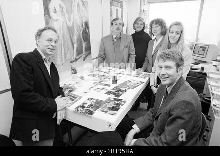 Vorsten editorial team, Whizgle News, Dutch Desk, The Netherlands, 1950 - 2000 on 11-10-1995. These are the elements in the image. In a bright, organized office setting, six individuals are gathered around a large table, which is covered with various photographs and documents. The panel of images includes a variety of colors, suggesting different topics or projects they are discussing. Among the group, there is a mix of both genders and various hair styles. The man in the foreground, wearing a dark blazer, appears confident, leaning slightly forward with a smile that conveys enthusiasm. To his Stock Photo
