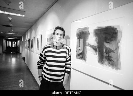 Artist Marc de Jong IJmuiden IJmuiden The Netherlands, Whizgle News, Dutch Desk, The Netherlands, 1950 - 2000 on 25-11-1991. The image shows these topics. The scene is set in a long, narrow gallery, characterized by a minimalistic design featuring clean lines and muted colors. The walls are predominantly white, providing a stark backdrop for the artwork displayed. Several abstract paintings, framed in simple white frames, hang lightly on the walls. The artwork seems to feature bold, brushstroke textures in shades of black, gray, and hints of earth tones, creating an engaging visual contrast ag Stock Photo