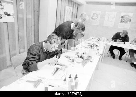 Airbrush course at Muys, Whizgle News, Dutch Desk, The Netherlands, 1950 - 2000 on 25-11-1990. These are the elements in the image. In a well-lit indoor space, a group of four individuals is engaged in a focused creative activity. The room features pale wooden walls which give it a warm, inviting atmosphere. Natural light streams in from above, enhancing the clarity of the scene. At the center of the composition is a long, rectangular table cluttered with various art supplies. Brightly colored bottles of paint—reds, blues, yellows, and greens—are arranged alongside brushes of different sizes a Stock Photo
