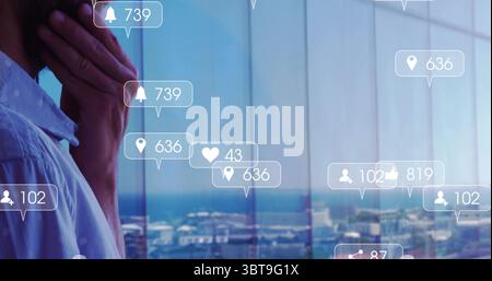 Standing man in blue shirt gazing at office window with ocean view, displaying alerts, copy space Stock Photo