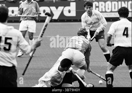 Hockey Bloemendaal - RC de Paris, Whizgle News, Dutch Desk, The Netherlands, 1950 - 2000 on 19-05-1994. These topics appear in the image. The scene captures a dynamic moment in a field hockey match. The players are focused on the action, displaying intense concentration and athleticism. In the foreground, two players battle for possession of the ball. One is wearing a bright red jersey, while the other, in a white kit with a long-sleeved shirt, appears to be attempting to make a pass or regain control. The player in red is crouched low, demonstrating agility and strategic positioning. Surround Stock Photo