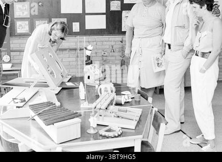 Open house daycare center De Luchtballon Heemskerk Children kid children's homes children's party children's Heemskerk, Whizgle News, Dutch Desk, The Netherlands, 1950 - 2000 on 19-06-1986. These topics are shown in the image. The scene unfolds in a brightly lit classroom setting with a cheerful, yet educational atmosphere. The walls are adorned with various drawings and projects, hinting at a creative environment filled with children's artwork. In the center, a wooden table dominates the space, cluttered with an assortment of colorful objects linked to learning and creativity. Among these, a Stock Photo