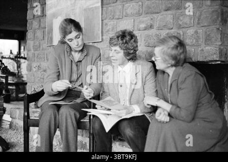 3 ladies deaf information Heemstede Information Persons Heemstede The Netherlands, Whizgle News, Dutch Desk, The Netherlands, 1950 - 2000 on 08-01-1981. These topics are shown in the image. In a cozy indoor setting characterized by a rustic stone wall, three women are engaged in a thoughtful conversation. The room exudes a warm ambiance, enhanced by a gentle glow from nearby lighting. The women sit close together on a dark wooden bench, creating an intimate group dynamic. Each one presents a distinct appearance: one wears a tailored blazer over a collared shirt, looking pensive as she holds an Stock Photo