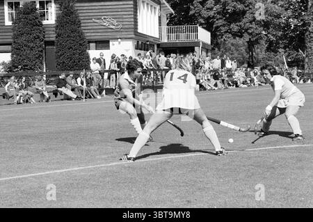 Hockey: Bloemendaal - Gooische Hockey, Whizgle News, Dutch Desk, The Netherlands, 1950 - 2000 on 15-09-1979. These topics are shown in the image. The scene depicts an energetic field hockey match set on a lush green field with a perfectly manicured appearance. The players are adorned in contrasting uniforms—one team wearing dark tops with light shorts and the opposing team dressed in pale attire. The athletes display dynamic poses, indicating an intense moment of competition; one player skillfully maneuvers the stick to control the ball, while two opponents are positioned ready to intercept. I Stock Photo