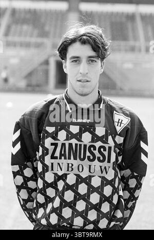 Haarlem players + team, Whizgle News, Dutch Desk, The Netherlands, 1950 - 2000 on 14-08-1995. The image contains these topics. A young athlete stands prominently in the foreground, exuding a focused and determined expression. He sports a striking black and white goalkeeper jersey adorned with a bold geometric pattern. The jersey features distinct diagonal stripes, and the brand logos are prominently displayed, adding a sense of professionalism. His hair is tousled, framing his face, which carries an air of confidence. The background consists of a blurred stadium setting, hinting at the energy Stock Photo
