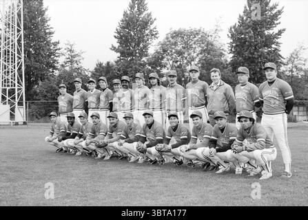 Portraits of players Ned. Baseball team Baseball characters, Whizgle News, Dutch Desk, The Netherlands, 1950 - 2000 on 22-06-1987. These are the topics in the image. The scene captures a baseball team positioned in a neatly organized formation on a grassy field. The players, dressed in matching uniforms, exhibit vibrant colors, primarily a combination of blue and white, with their team logo prominently displayed on their jerseys. Their caps coordinate with the uniform colors, further emphasizing team spirit. They are lined up in two rows, with the back row standing tall and the front row kneel Stock Photo