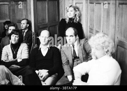 General considerations Zandvoort (about circuit) Circuit Zandvoort Zandvoort Municipal Council Zandvoort, Whizgle News, Dutch Desk, The Netherlands, 1950 - 2000 on 19-11-1979. These topics are shown in the image. The scene captures a group of people seated in a dimly lit, intimate setting, likely within a conference room or a small auditorium. The walls are made of wooden panels, contributing to a warm yet somber atmosphere. To the left, a woman with dark hair and a patterned sweater sits with her arms crossed, exuding a sense of contemplation. Next to her, a man with a bald head and a neatly Stock Photo