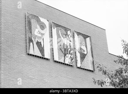 Unveiling wall drawings school music-ballet Hillegom Unveilings Hillegom, Whizgle News, Dutch Desk, The Netherlands, 1950 - 2000 on 11-10-1986. The image contains these topics. The scene presents a series of three large, rectangular artworks mounted on a textured brick wall. Each piece features bold, abstract designs characterized by strong lines and contrasting shapes. The color palette is monochromatic, dominated by shades of gray and black, giving the artworks a striking yet subdued presence. The first panel on the left showcases an intricate interplay of curved and angular forms that sugge Stock Photo