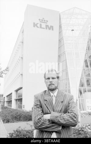 Chairman CNV Schiphol East Bonden Schiphol, Whizgle News, Dutch Desk, The Netherlands, 1950 - 2000 on 16-09-1988. The image shows these topics. In a setting that features a modern building with a blend of angular and geometric designs, a man stands prominently in the foreground. His attire consists of a pinstriped suit that contrasts sharply with the building's clean lines. The suit presents a formal and serious aesthetic, enhanced by the man's composed posture and crossed arms, which convey a sense of confidence or authority. The building behind him showcases a combination of smooth, white co Stock Photo