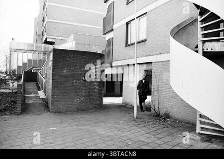 Mr. De Graaf welfare work Haarlem Haarlem The Netherlands, Whizgle News, Dutch Desk, The Netherlands, 1950 - 2000 on 18-11-1997. These topics appear in the image. The scene captures an urban landscape with a mix of architectural structures and natural elements. The buildings feature a combination of brick and concrete, characterized by rectangular shapes and angular designs, contributing to a modernist aesthetic. In the foreground, a spiral staircase gracefully curves upwards, its metallic surface reflecting subtle light. To the left, a textured brick wall separates two sections of the space, Stock Photo