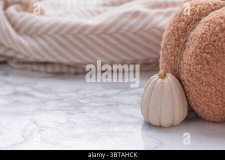 Stylish flat lay for fall featuring handmade fluffy pumpkin, decorative mini pumpkin and warm tones on a clean marble surface Stock Photo