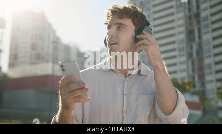 Happy Caucasian man smiling enjoyment listening music headphones earphones electronic gadget device technology favorite song guy businessman mobile Stock Photo