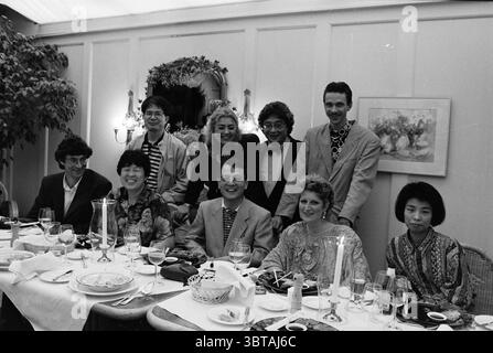 Group of Japanese B'broek Bennebroek, Whizgle News, Dutch Desk, The Netherlands, 1950 - 2000 on 17-07-1992. These topics appear in the image. In a well-decorated dining room, a group of nine individuals gathers around a long, elegantly set table. The table is adorned with white tablecloths and fine glassware, displaying a subtle sophistication. The scene is bustling with life, laughter, and camaraderie. The group consists of a mix of men and women, showcasing a variety of fashion styles. Some wear tailored suits, while others don vibrant patterns and colors that speak to a lively, eclectic sen Stock Photo