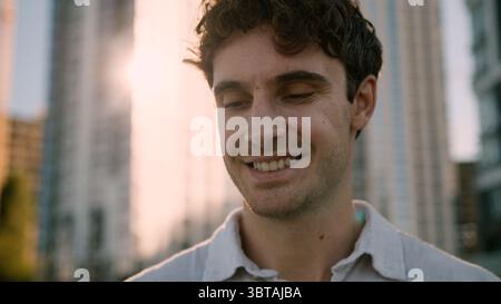 Close up face happy Caucasian European man looking down smiling young guy male holding mobile phone gadget expression student worker entrepreneur Stock Photo
