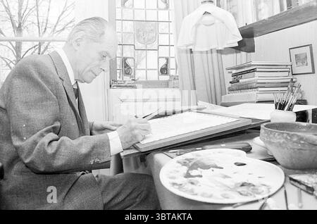 Anton Pieck behind his drawing board., Whizgle News, Dutch Desk, The Netherlands, 1950 - 2000. The image shows these topics. A man is seated at a wooden desk, deeply engaged in his work. He has silver hair that’s neatly combed back, and he wears a gray suit that adds a touch of sophistication to the scene. His focus is on a sheet of paper resting on the desk as he carefully adds details with a pen. The workspace around him is arranged with various artist supplies. A palette filled with a vibrant assortment of colors lies to his right, showcasing smudges of blue, red, and yellow. Several brushe Stock Photo