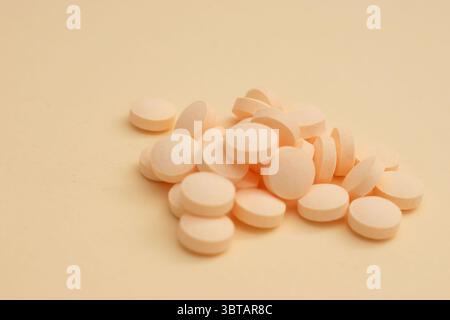 Minimal concept with white round pills in glass container and spoon on beige background Stock Photo