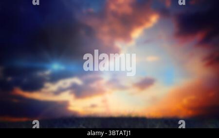 Sunset sky is showing multicolored clouds over lit grassy meadow in flat design with sun rays Stock Photo