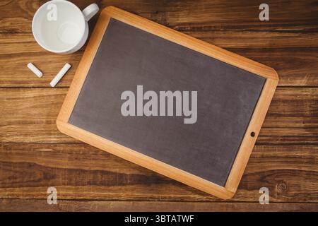Flat design showing wood-frame chalkboard on wood-grain tabletop with chalk sticks, ceramic mug Stock Photo