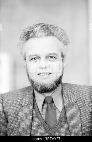 Portraits of three members of parliament Prov. States Prov. Water Management Provincial House, Whizgle News, Dutch Desk, The Netherlands, 1950 - 2000 on 08-02-1981. These are the topics in the image. The scene features a man with a full, gray beard and well-groomed hair, which is also gray and slightly unkempt. His expression is neutral, with a hint of a smile, suggesting confidence. He wears a tailored suit with a textured, light-colored blazer, complemented by a darker tie and a knitted vest underneath, creating a layered appearance. The background is softly blurred, which directs attention Stock Photo
