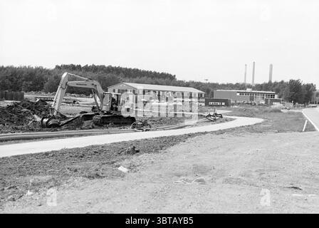 Overview of preparations for the Wijkertunnel, Whizgle News, Dutch Desk, The Netherlands, 1950 - 2000 on 31-05-1993. These are the elements in the image. The scene features a large construction area characterized by earth being excavated and transformed. In the foreground, a gray excavator is prominently positioned, its arm extended as it digs into the brown soil. This vehicle is detailed with varying shades of gray and green, showing signs of usage. To the left, the ground is uneven, revealing sections of freshly turned earth scattered with rocks and small debris. Semi-circular dirt piles lie Stock Photo