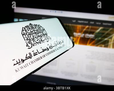 In this photo illustration, a smartphone with the logo of Kuwait Chamber of Commerce and Industry KCCI is seen on screen in front of website. Stock Photo