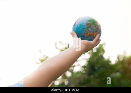 A young boy's hand is holding a globe in the air with copy space. Earth conservation concept Stock Photo