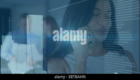 Talking on smartphone, woman in sleeveless top at office, with monitors, chart overlays, copy space Stock Photo