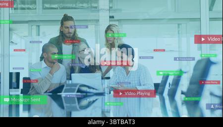 Collaborating five professionals showing software features in glass office, with laptops and tablet Stock Photo