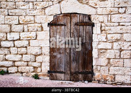 close vintage wooden door set in a stone wall of an ancient farmhouse Stock Photo