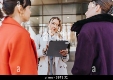 Three businesswomen collaborating on a project using a digital tablet outdoors Stock Photo