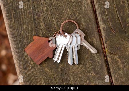 Bunch of keys with house keychain on wooden old cracked garden outdoor table. Top view Stock Photo