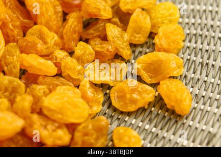 Dried dehydrated yellow raisins on wicker green kitchen mat. Top view. Stock Photo