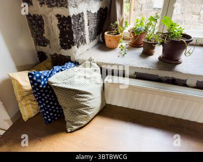 A wooden bench with pillows on it. There are six pillows on the bench. The pillows are in different colors and patterns Stock Photo
