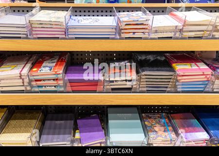 Poznan, Poland - June 30, 2025: Variety of colorful notebooks, diaries, and academic planners neatly displayed on wooden store shelves, perfect for st Stock Photo
