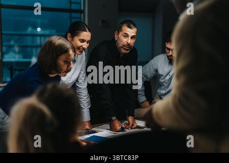 Diverse team collaboratively brainstorming ideas in a late evening meeting Stock Photo