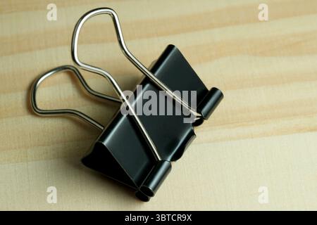 Stationery binder clip on a wooden table, close-up Stock Photo