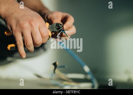 Close-up of hands using cutting pliers to work on electrical wires during a repair job Stock Photo