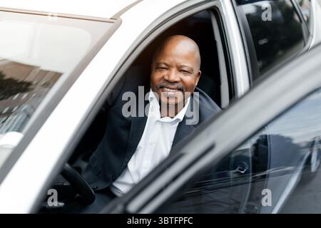 Black businessman in suit getting out of car with smile Stock Photo