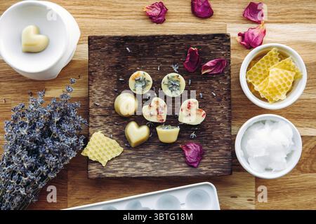 Making of mini wax melts for aroma lamp at home concept. Tools ingredients on table unbleached beeswax, solid coconut oil, essential oil, dried flower Stock Photo